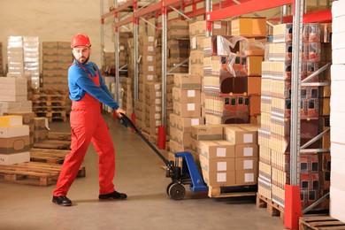 Image of Worker with pallet jack at warehouse. Logistics center