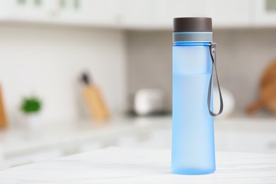 Stylish bottle of water on table in kitchen. Space for text