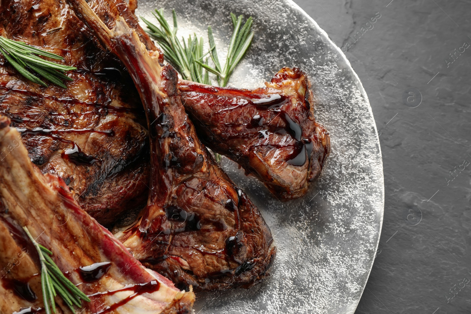 Photo of Delicious grilled ribs on black table, closeup