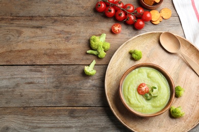 Photo of Flat lay composition with bowl of broccoli cream soup on wooden table, space for text