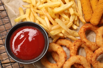 Tasty ketchup with snacks on wooden table, closeup