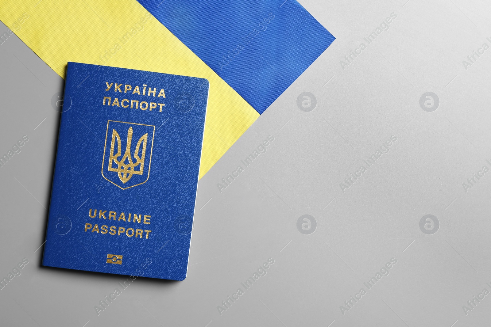 Photo of Ukrainian travel passport and national flag on grey background, top view with space for text. International relationships