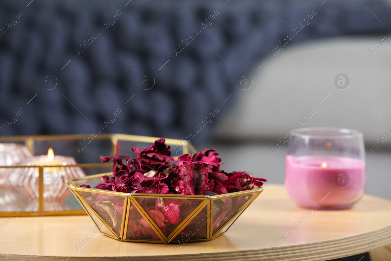 Photo of Aromatic potpourri of dried flowers in decorative bowl and burning candles on table indoors, space for text