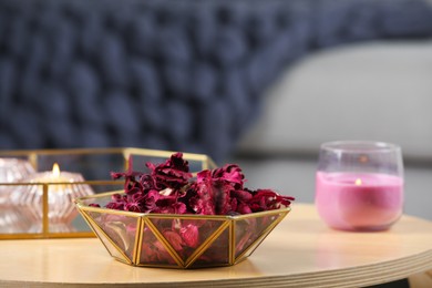 Aromatic potpourri of dried flowers in decorative bowl and burning candles on table indoors, space for text