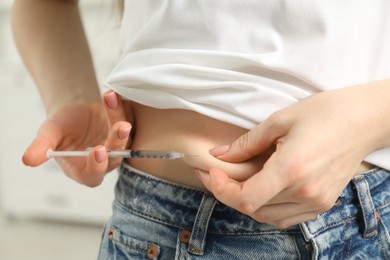 Photo of Diabetes. Woman making insulin injection into her belly indoors, closeup