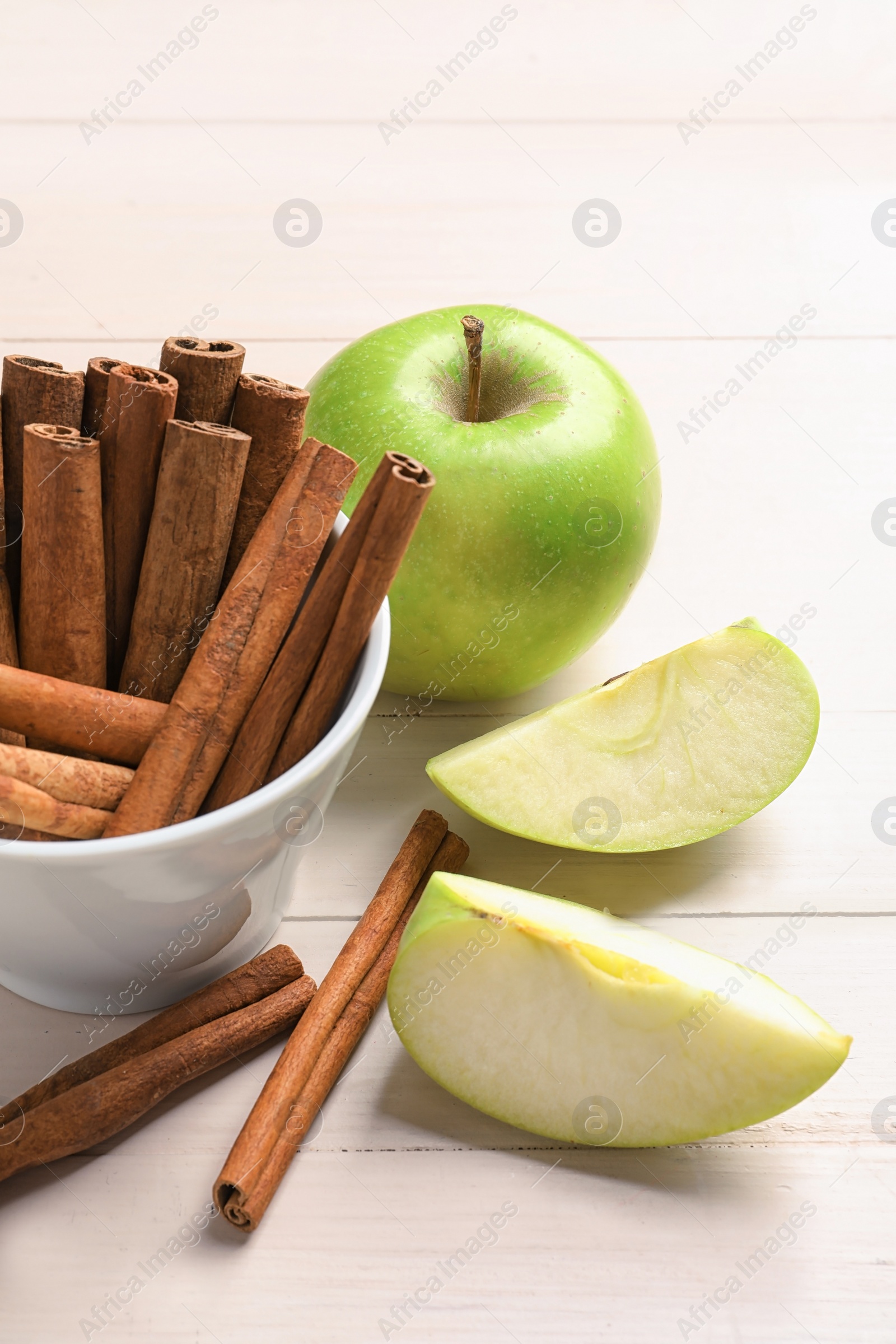 Photo of Fresh apples and cinnamon sticks on table