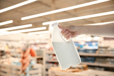 Image of Woman holding gallon bottle of milk in supermarket, closeup