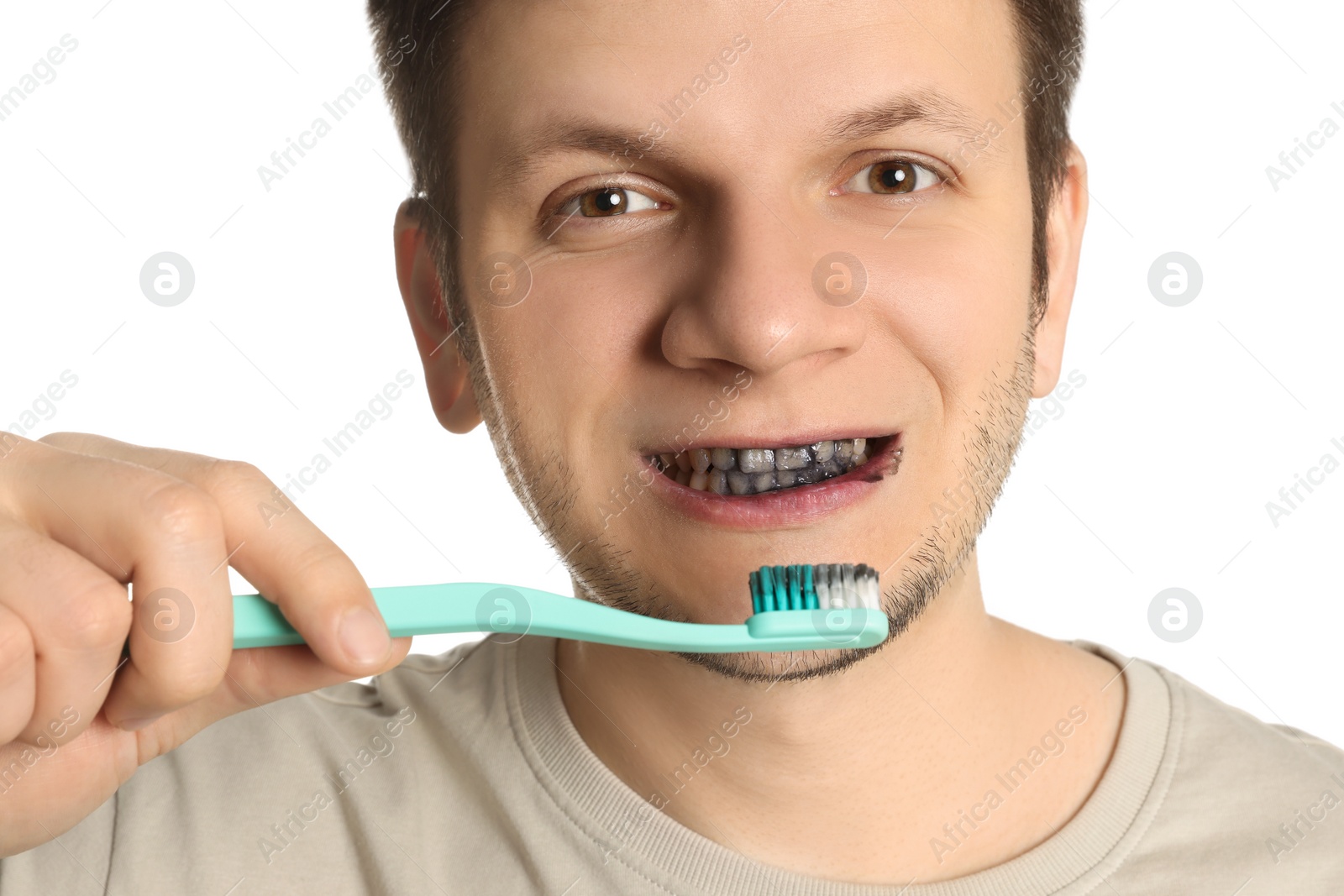 Photo of Man brushing teeth with charcoal toothpaste on white background, closeup