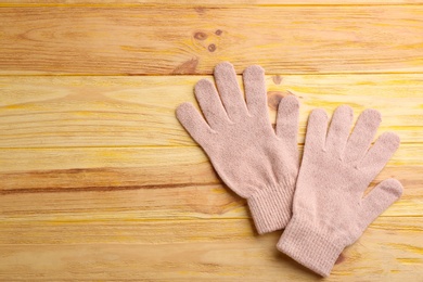Stylish pink gloves on wooden background, flat lay. Space for text