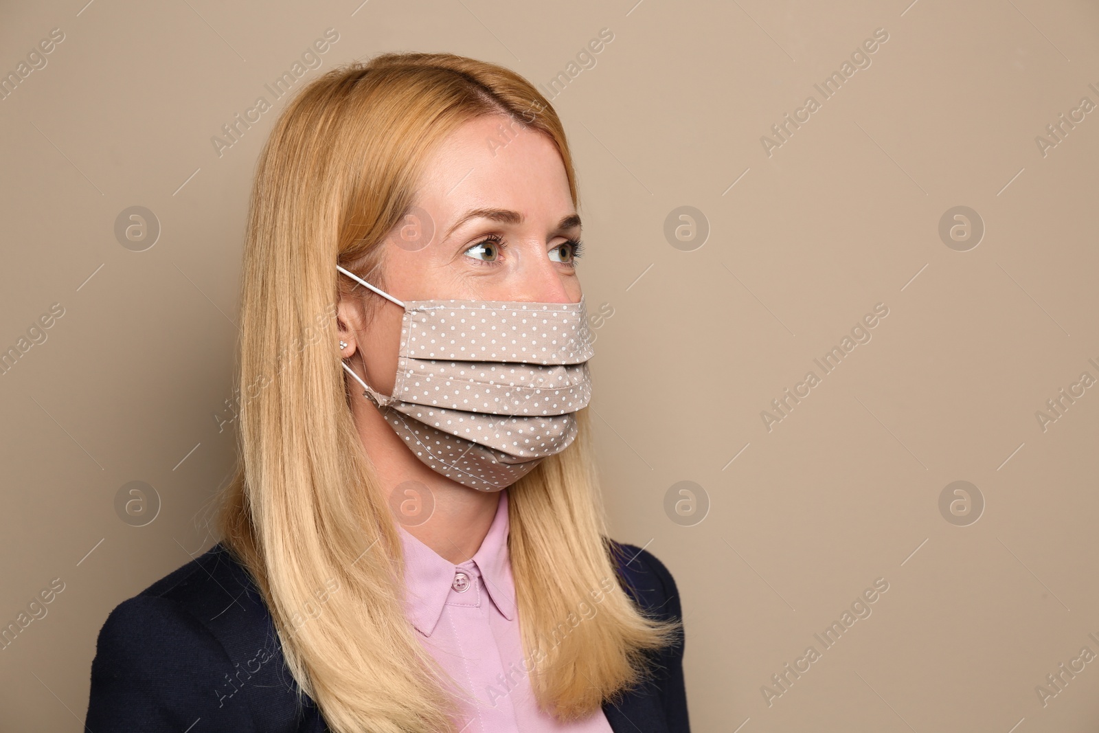 Photo of Woman wearing handmade cloth mask on beige background, space for text. Personal protective equipment during COVID-19 pandemic