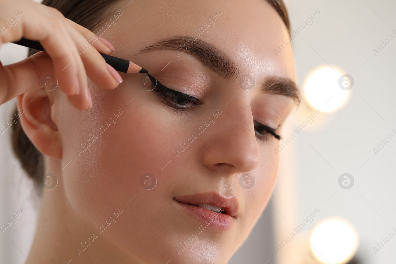 Photo of Makeup product. Woman applying black eyeliner indoors, closeup