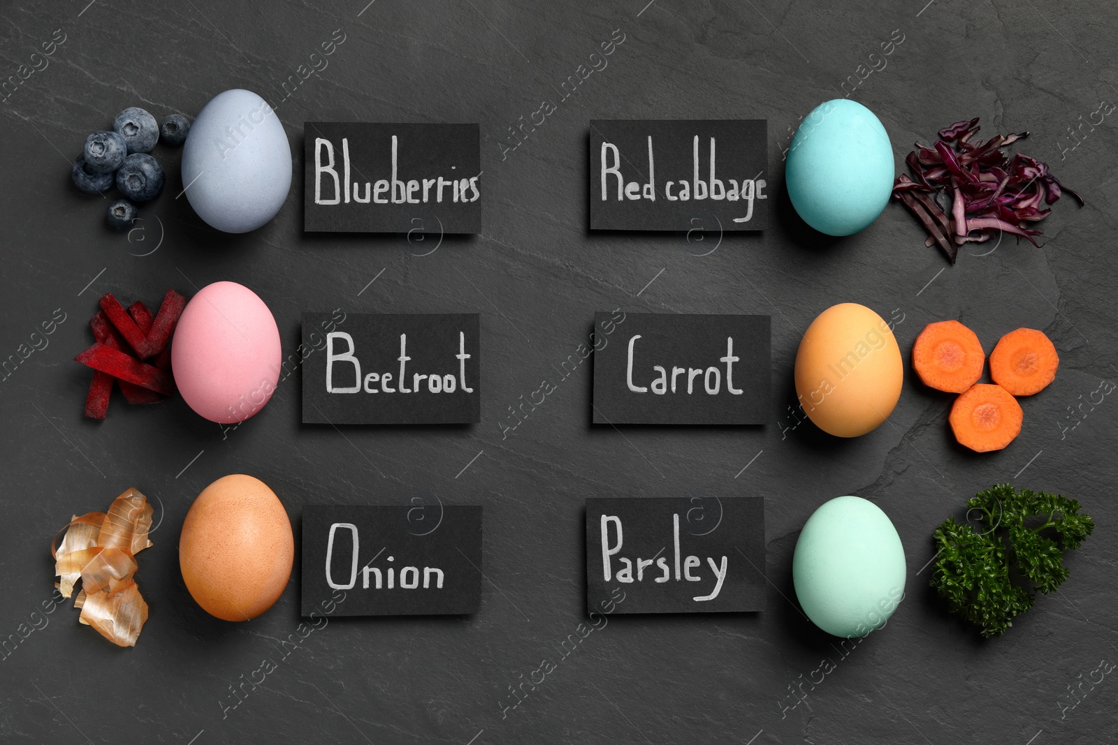 Photo of Naturally painted Easter eggs on black table, flat lay. Blueberries, beetroot, onion, red cabbage, carrot and parsley used for coloring