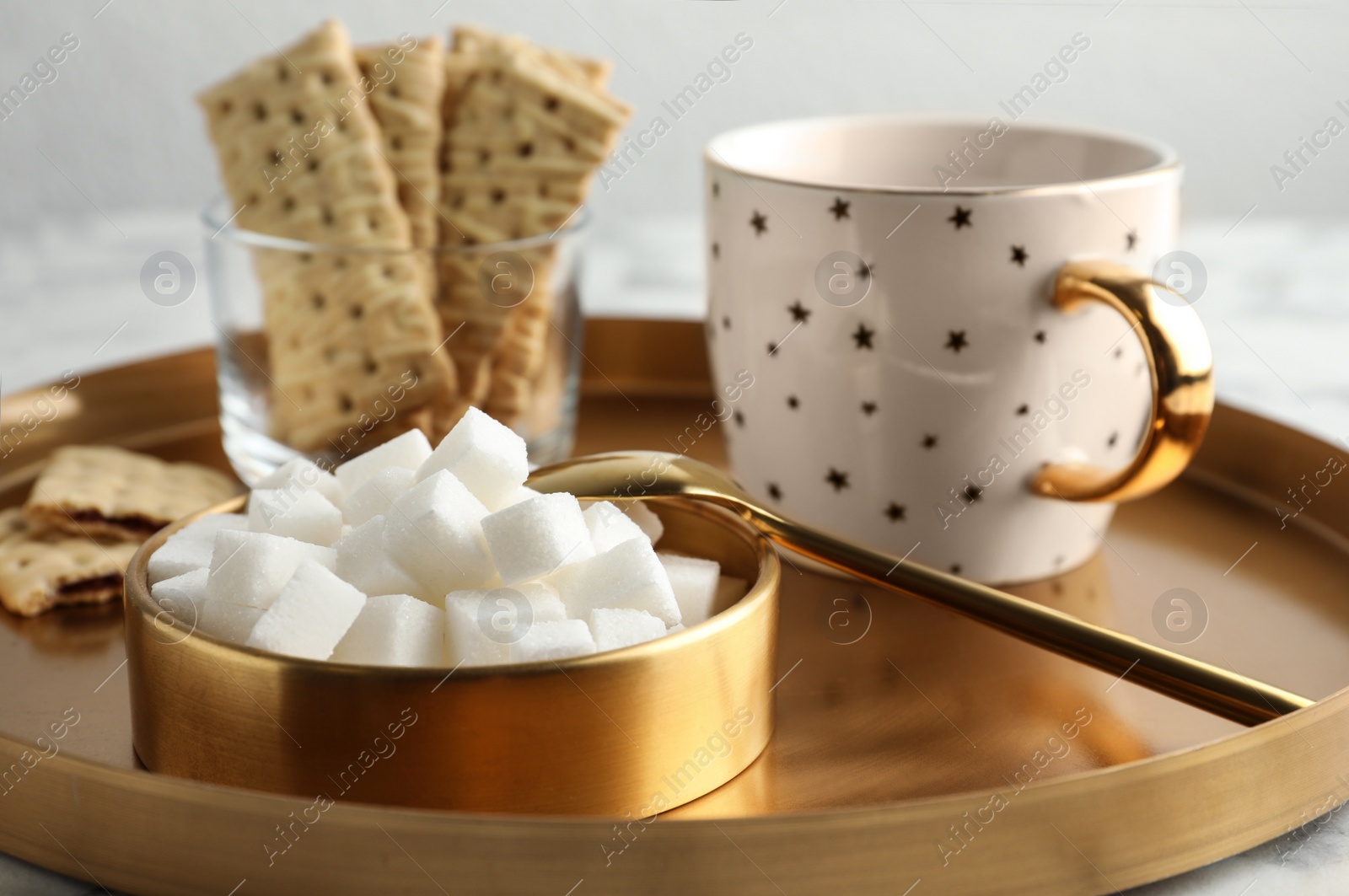 Photo of Refined sugar cubes in bowl and aromatic tea on table