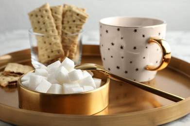 Refined sugar cubes in bowl and aromatic tea on table