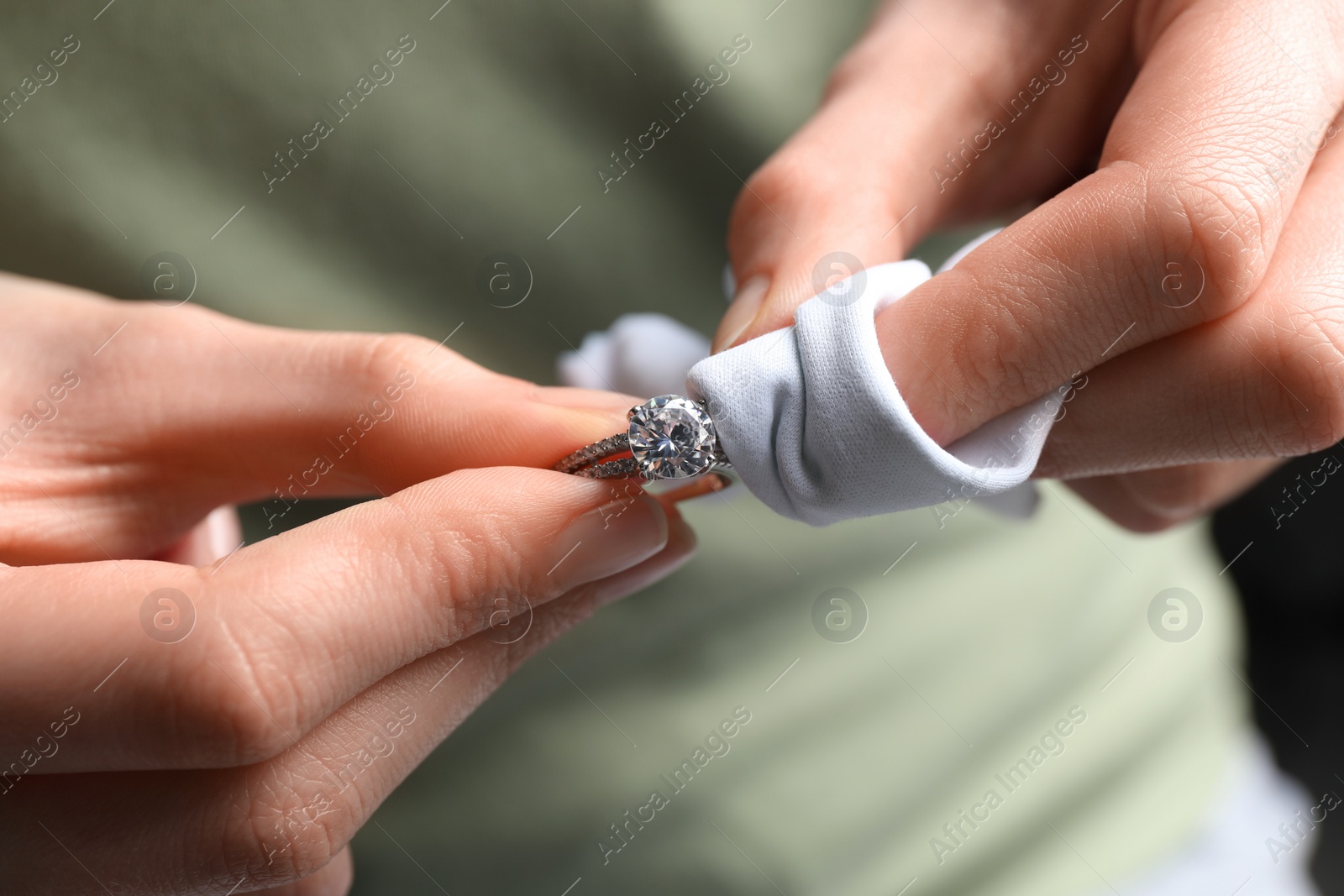 Photo of Jeweler cleaning diamond ring with microfiber cloth, closeup