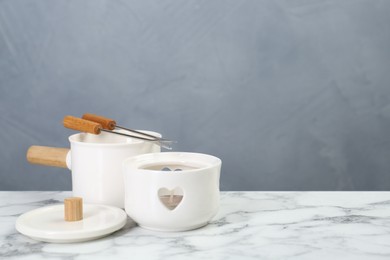 Fondue set on white marble table against light grey background, space for text