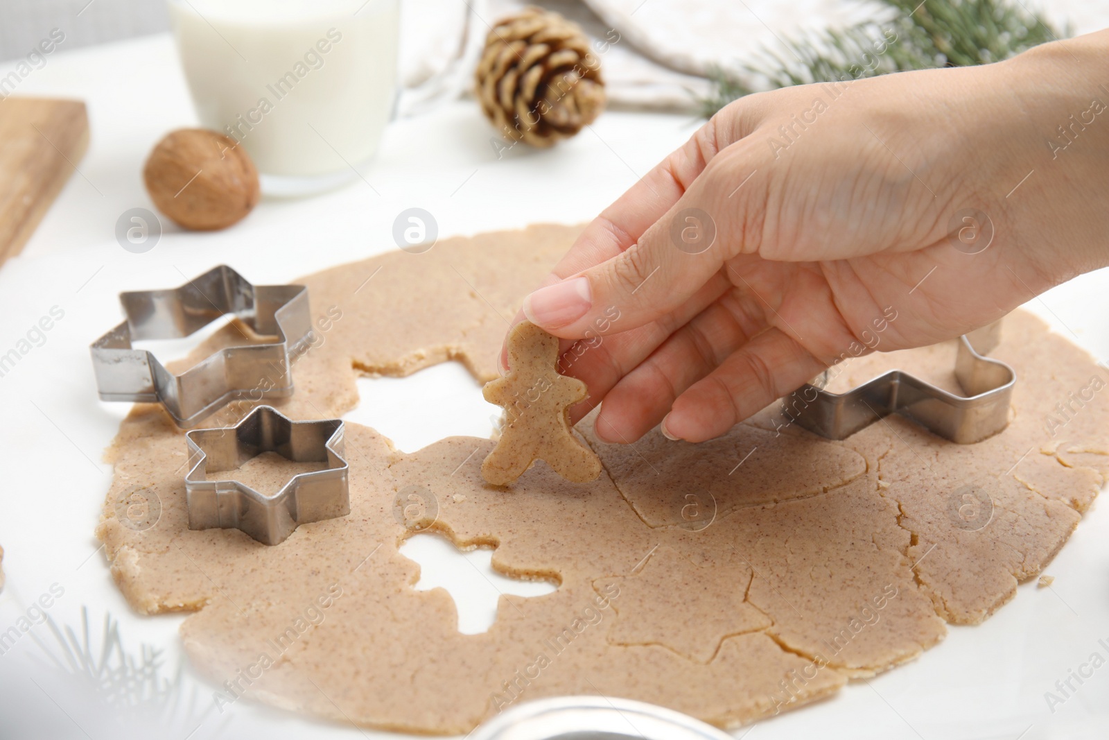Photo of Woman holding gingerbread man at white table, closeup. Homemade Christmas cookies