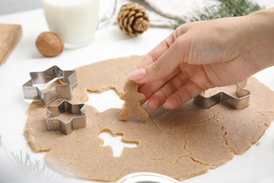 Photo of Woman holding gingerbread man at white table, closeup. Homemade Christmas cookies
