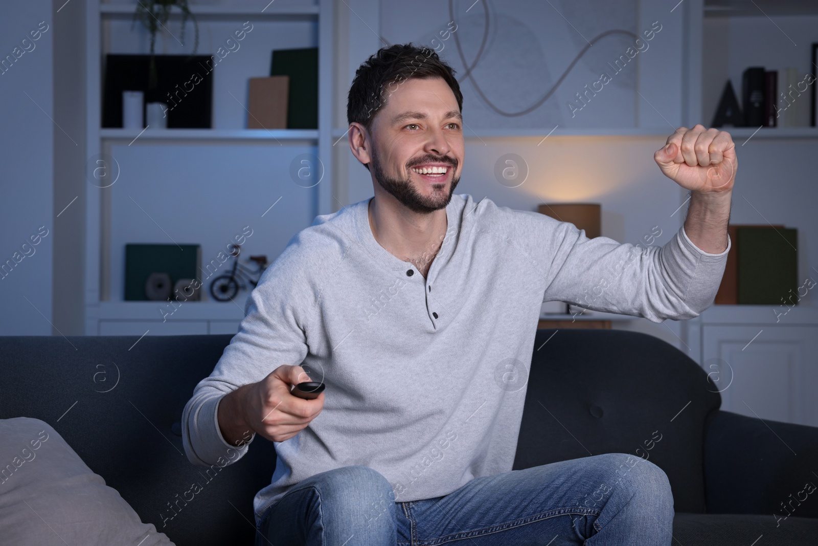 Photo of Emotional man watching TV on sofa at home