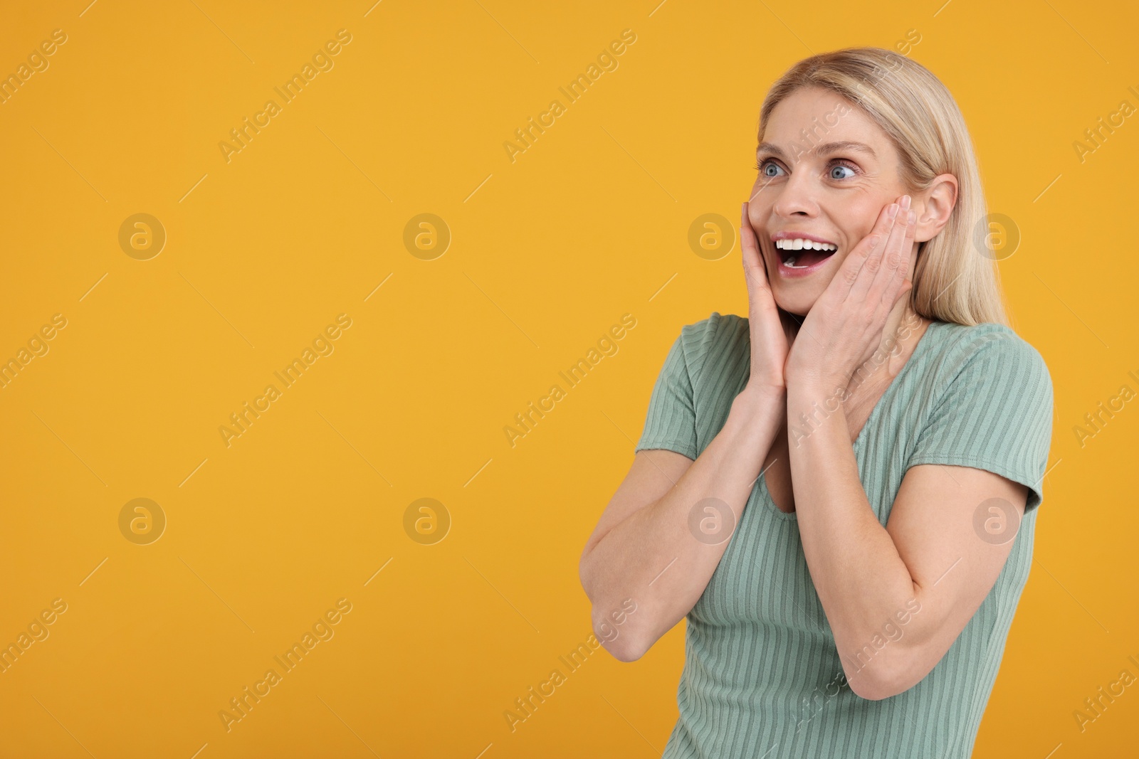 Photo of Portrait of happy surprised woman on yellow background, space for text