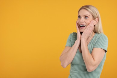 Photo of Portrait of happy surprised woman on yellow background, space for text