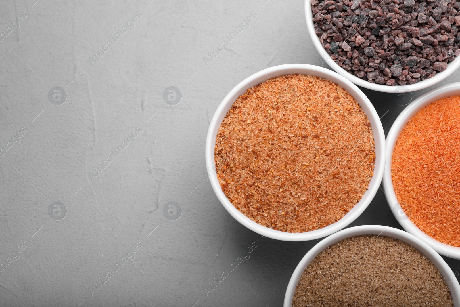 Photo of Different kinds of salt on light grey table, flat lay. Space for text