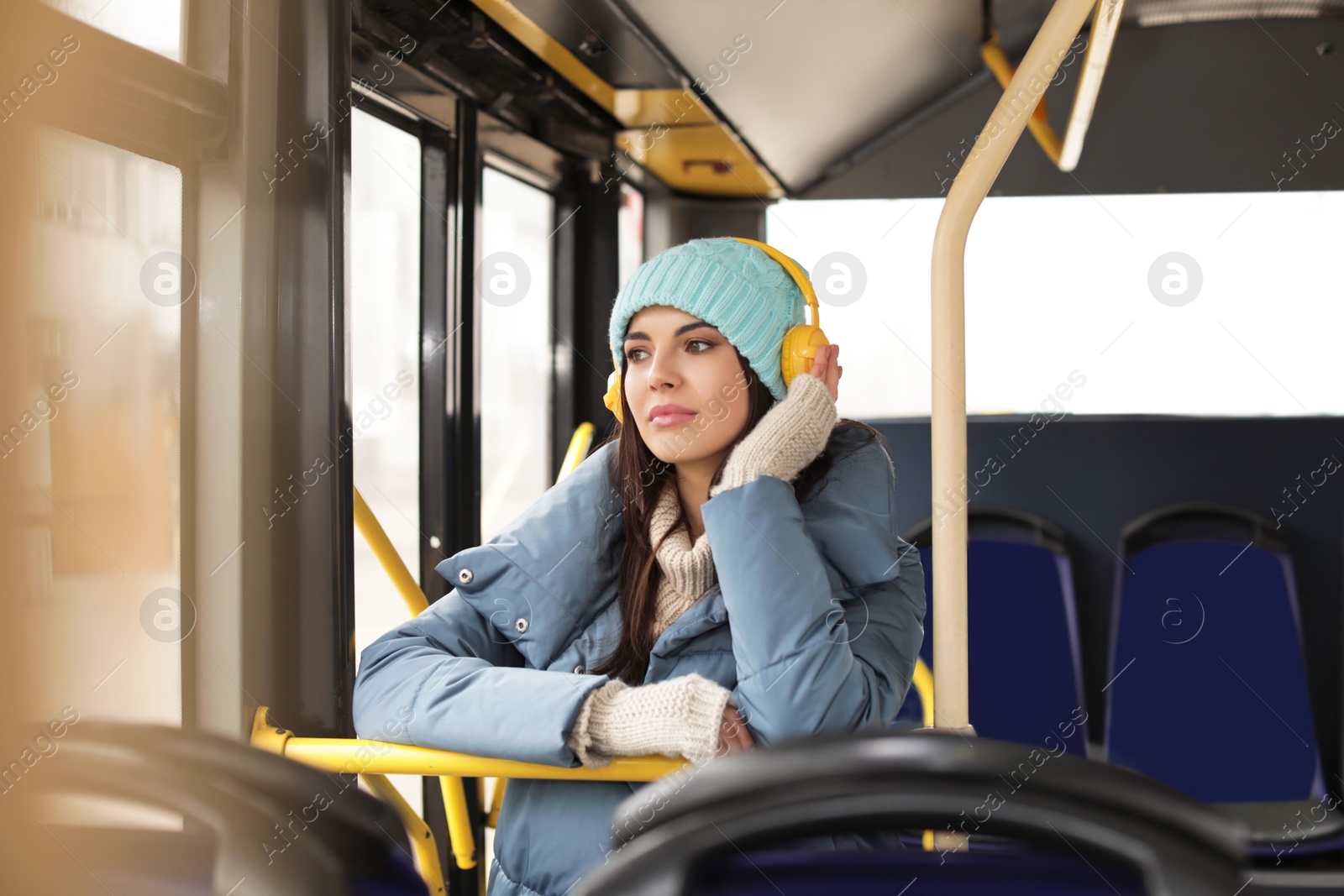 Photo of Young woman listening to music with headphones in public transport