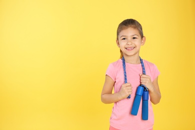 Cute girl with jump rope on color background. Space for text