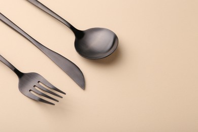 Photo of Stylish cutlery set on beige table, space for text