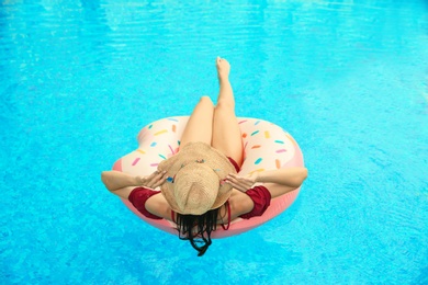 Photo of Beautiful young woman on inflatable ring in swimming pool