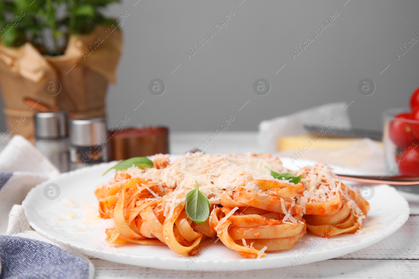 Photo of Delicious pasta with tomato sauce, chicken and parmesan cheese on white wooden table