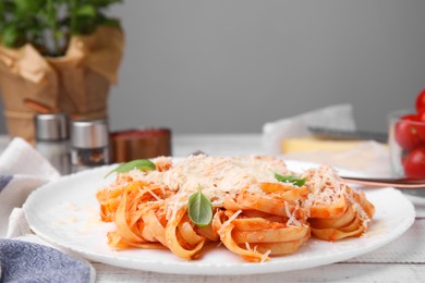 Delicious pasta with tomato sauce, chicken and parmesan cheese on white wooden table