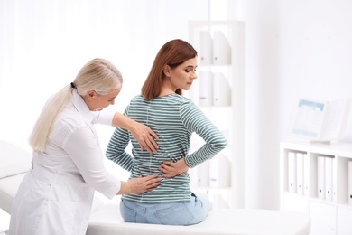 Chiropractor examining patient with back pain in clinic