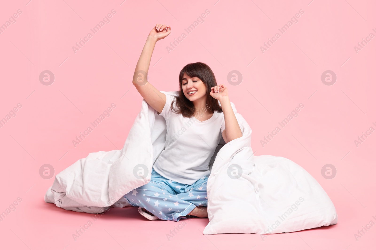Photo of Happy woman in pyjama wrapped in blanket on pink background