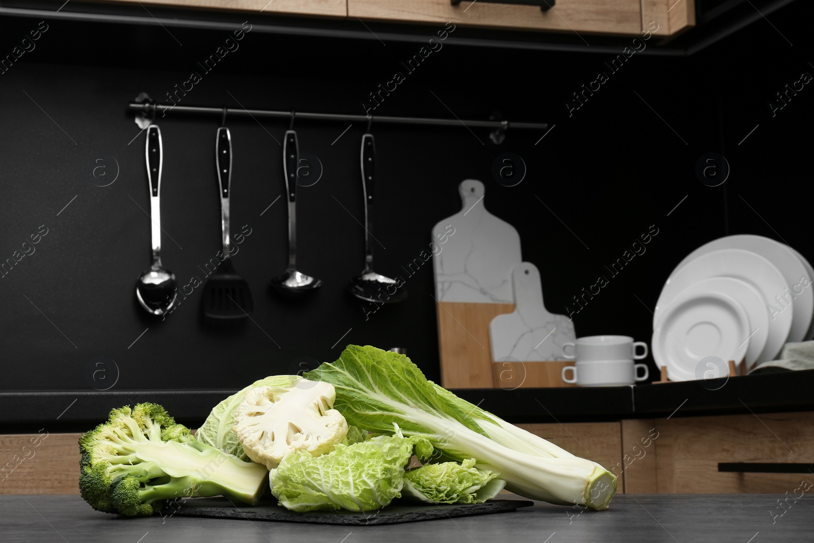 Photo of Different types of cut cabbage on grey table in kitchen, space for text