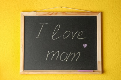 Photo of Chalkboard with phrase I LOVE MOM hanging on yellow wall