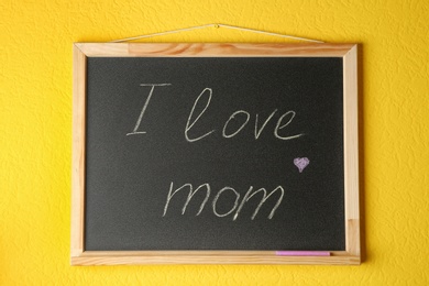 Chalkboard with phrase I LOVE MOM hanging on yellow wall