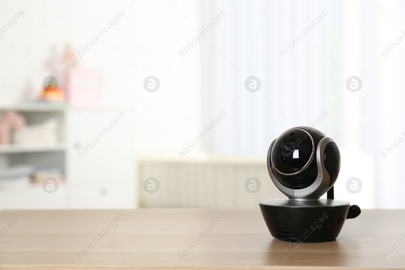 Photo of Baby camera on table in room, space for text. Video nanny