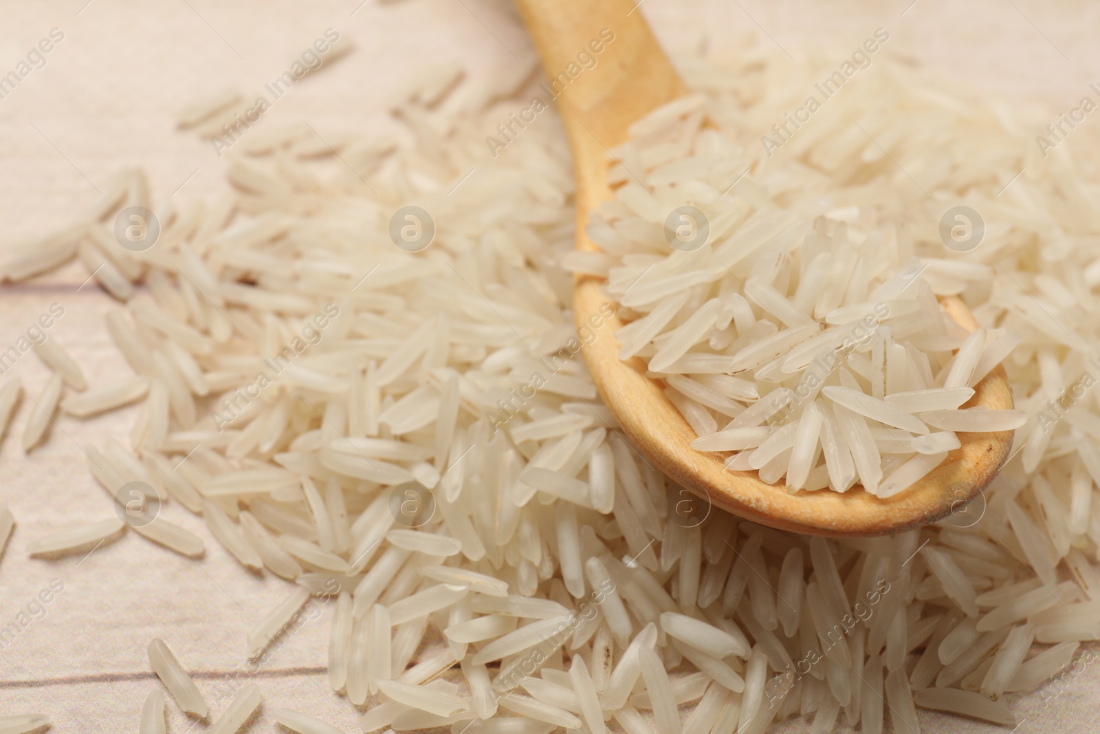 Photo of Raw basmati rice and spoon on white wooden table, closeup