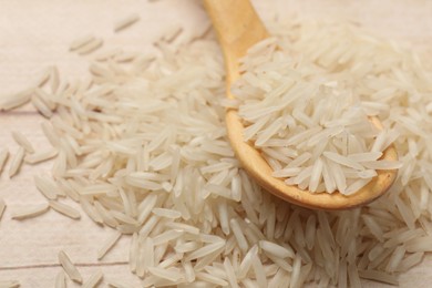 Photo of Raw basmati rice and spoon on white wooden table, closeup