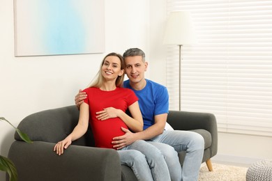 Young family housing concept. Pregnant woman with her husband on sofa at home