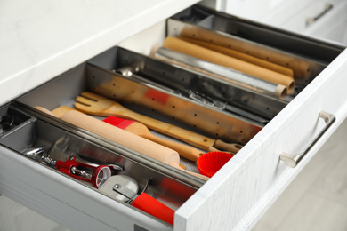 Photo of Different utensils in open desk drawer indoors, closeup