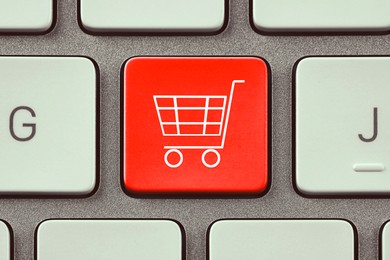 Image of Online store purchase. Red button with shopping cart on computer keyboard, top view