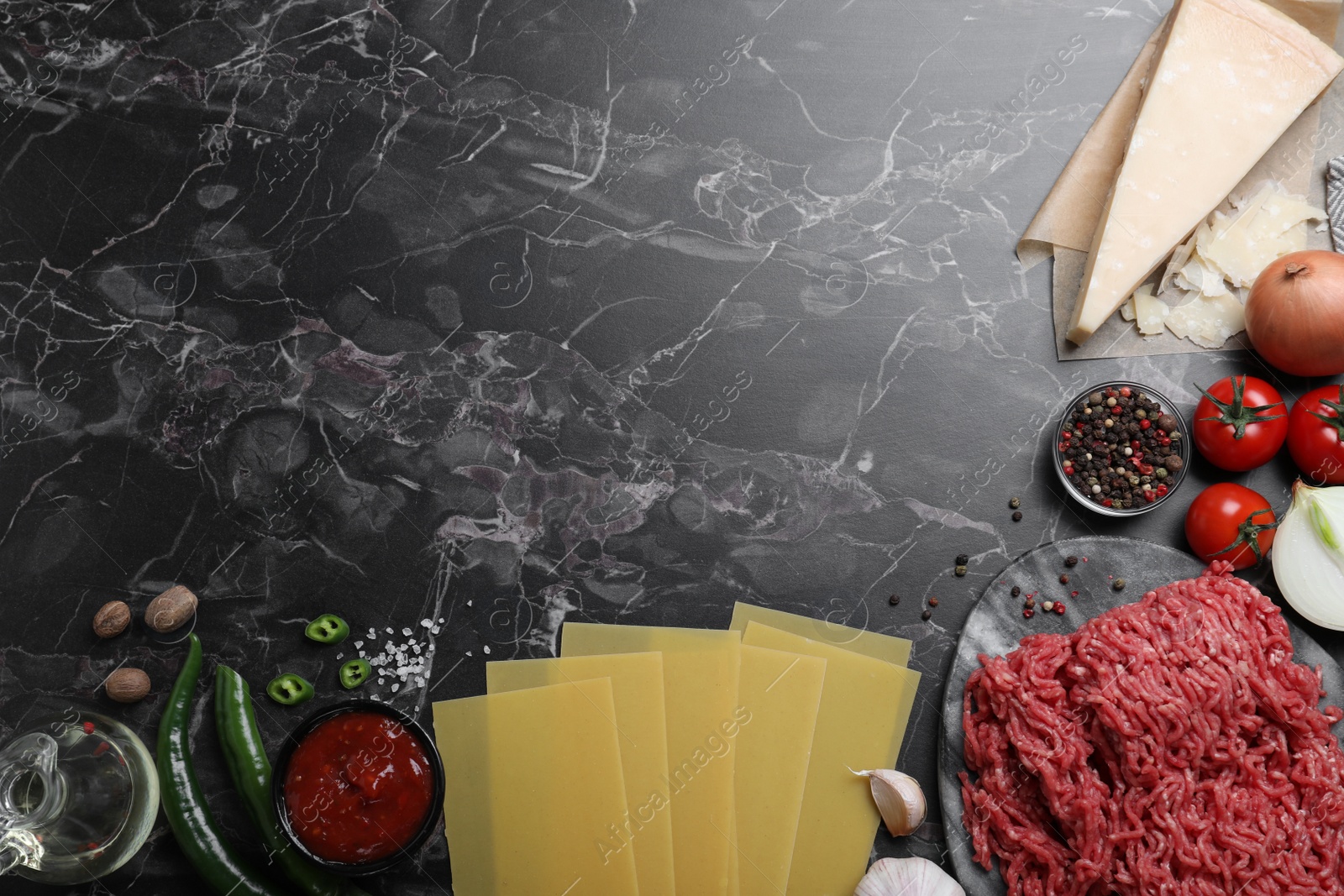 Photo of Fresh lasagna ingredients on black marble table, flat lay. Space for text