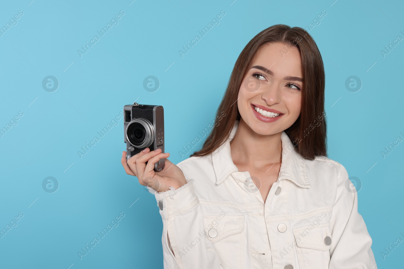 Photo of Young woman with camera on light blue background, space for text. Interesting hobby