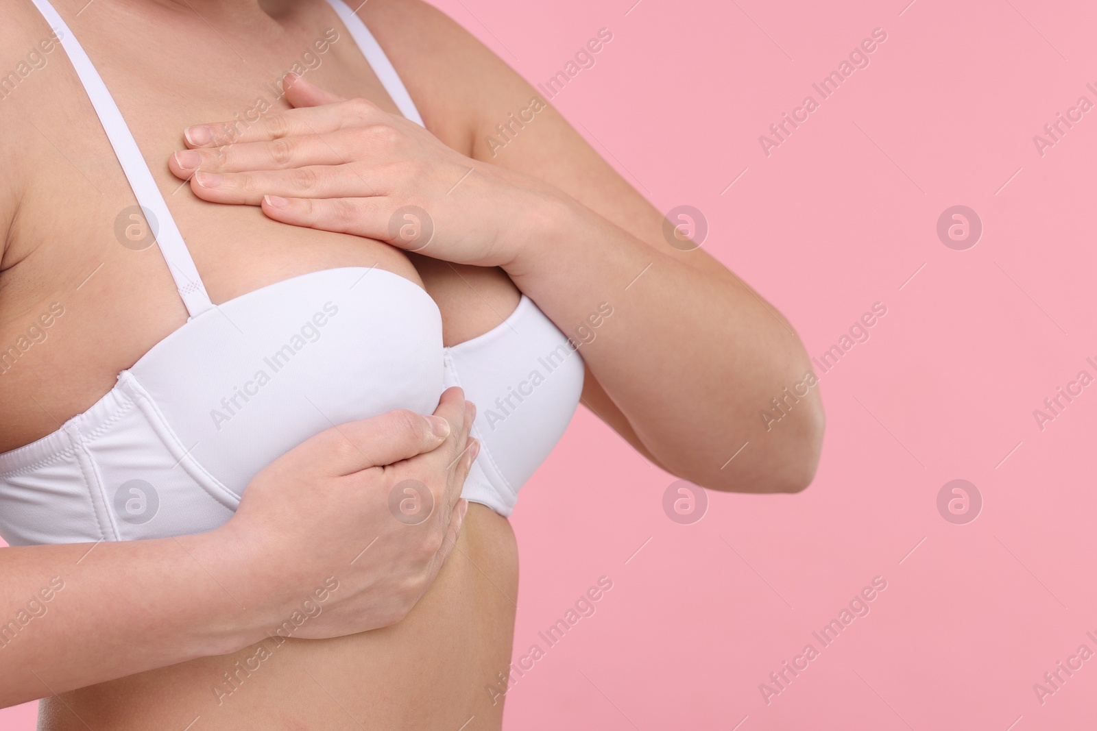 Photo of Mammology. Woman in bra doing breast self-examination on pink background, closeup and space for text