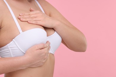 Photo of Mammology. Woman in bra doing breast self-examination on pink background, closeup and space for text