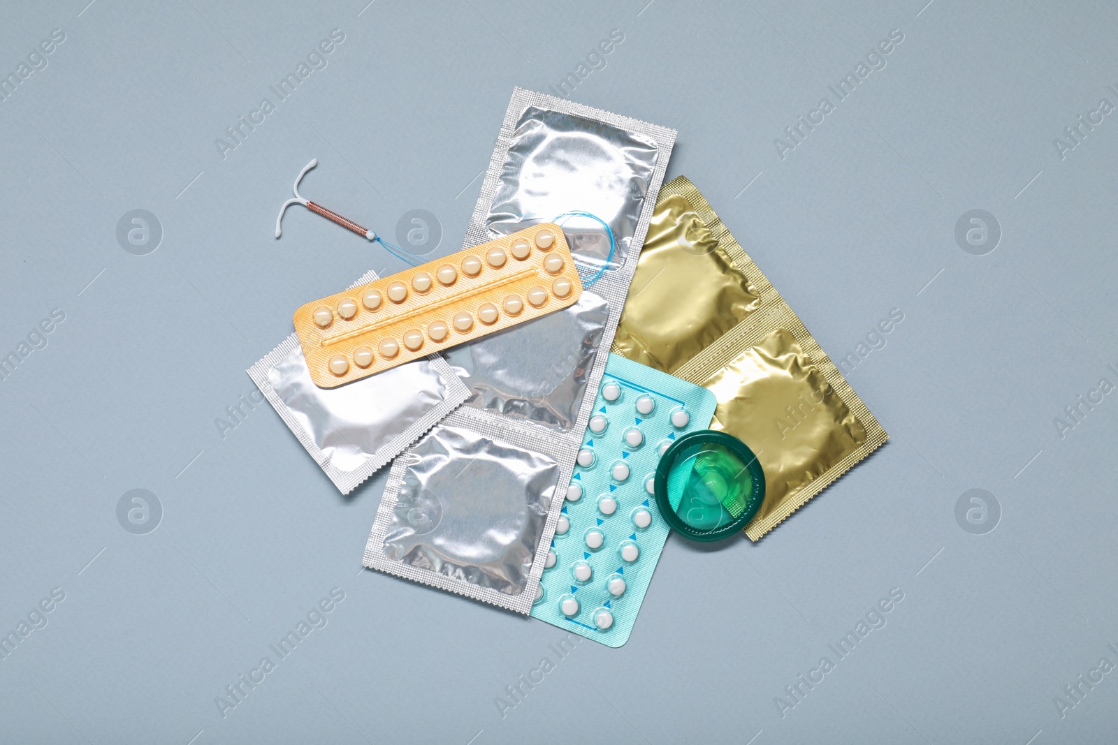 Photo of Contraceptive pills, condoms and intrauterine device on light grey background, flat lay. Different birth control methods