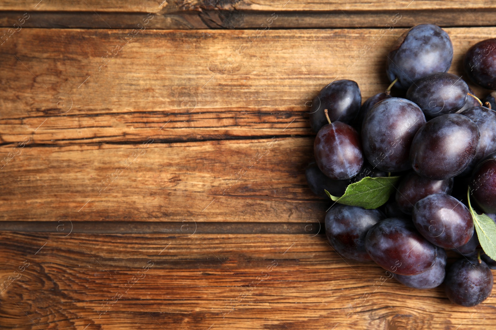 Photo of Delicious ripe plums on wooden table, flat lay. Space for text