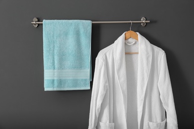 Photo of Hanger with clean towel and bathrobe on grey wall